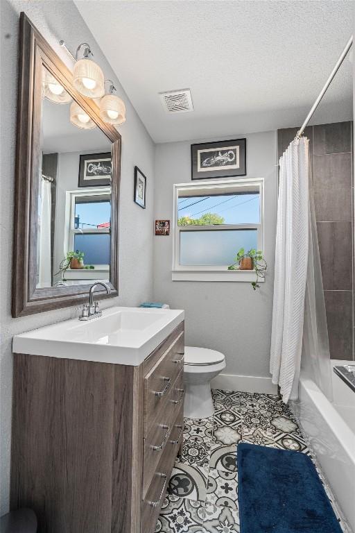 full bathroom with shower / tub combo, a textured ceiling, toilet, vanity, and tile patterned flooring