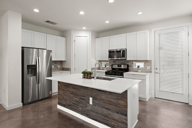 kitchen featuring sink, white cabinetry, tasteful backsplash, a center island with sink, and appliances with stainless steel finishes