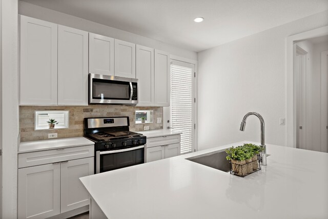 kitchen with white cabinetry, stainless steel appliances, sink, and decorative backsplash