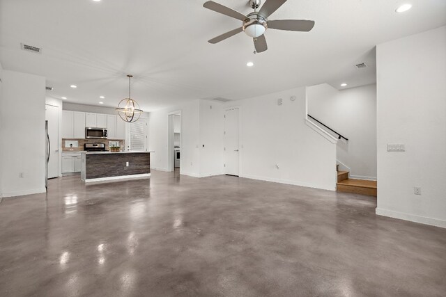 unfurnished living room with ceiling fan with notable chandelier and concrete floors