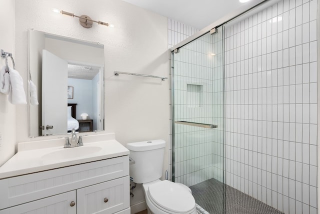 bathroom with a shower with door, vanity, and toilet