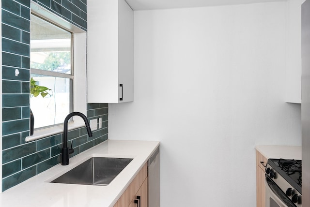 kitchen with gas stove, plenty of natural light, decorative backsplash, and sink