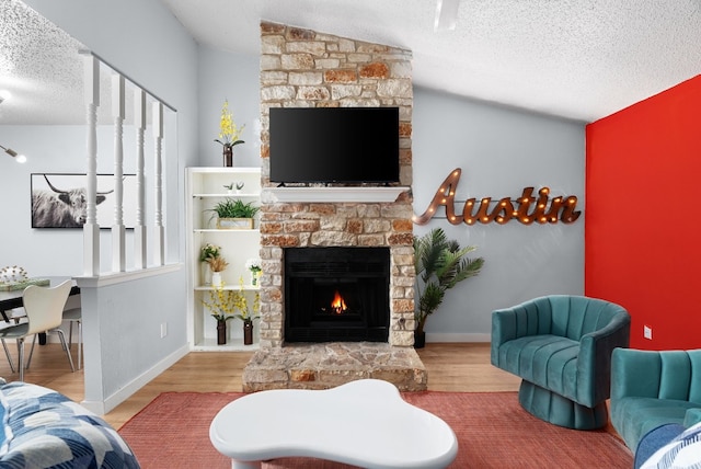 living room with lofted ceiling, light hardwood / wood-style flooring, a textured ceiling, and a stone fireplace