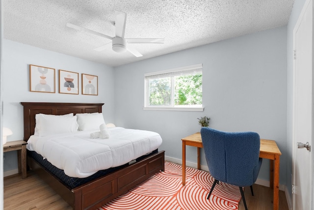 bedroom with hardwood / wood-style floors, ceiling fan, and a textured ceiling