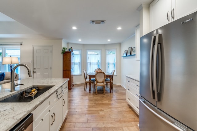 kitchen featuring light stone countertops, stainless steel appliances, and white cabinets