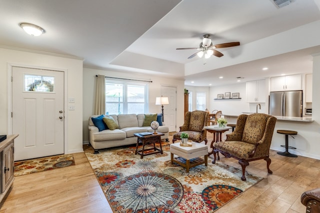 living room with crown molding, light hardwood / wood-style flooring, and ceiling fan