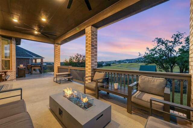 patio terrace at dusk featuring an outdoor living space with a fire pit and ceiling fan