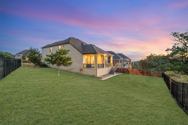 back house at dusk with a lawn