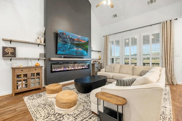 living room with high vaulted ceiling, light hardwood / wood-style floors, and ceiling fan