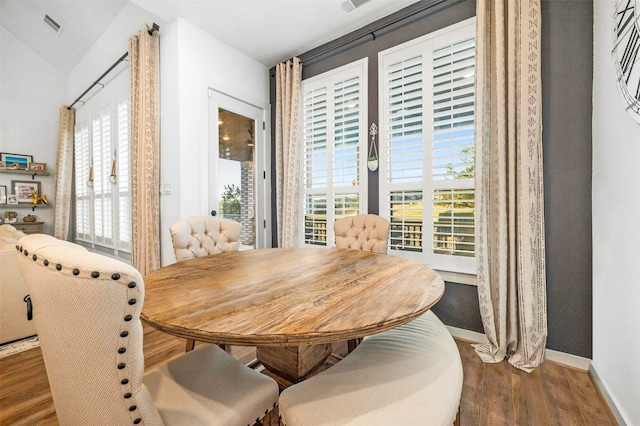 dining space featuring lofted ceiling and dark wood-type flooring