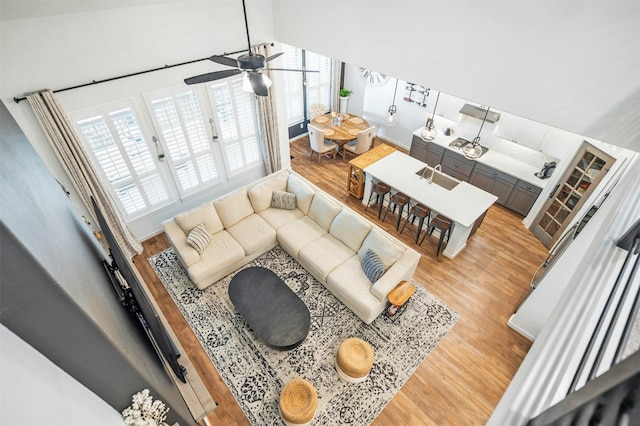 living room with vaulted ceiling, ceiling fan, sink, and light hardwood / wood-style floors