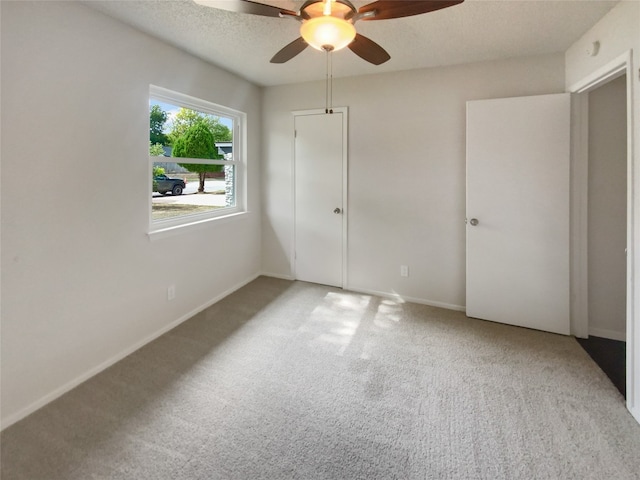 unfurnished bedroom featuring a textured ceiling, ceiling fan, and light carpet