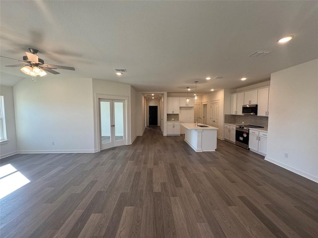 kitchen with decorative light fixtures, dark hardwood / wood-style floors, an island with sink, stainless steel appliances, and white cabinets