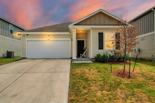 view of front of property with a garage, a yard, and cooling unit