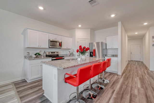 14601 Shooter Mc Gavin Dr, Manor, TX 78653 - kitchen featuring stainless steel appliances, light wood finished floors, white cabinets, a breakfast bar, and recessed lighting