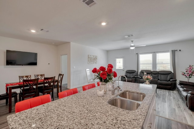 kitchen featuring a breakfast bar area, sink, white cabinetry, and light hardwood / wood-style flooring