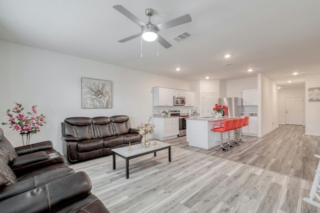 living room featuring ceiling fan and light hardwood / wood-style floors