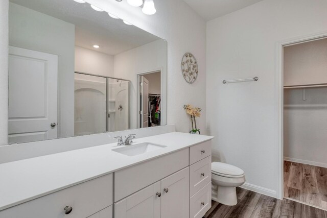 bathroom with a shower with door, vanity, toilet, and wood-type flooring