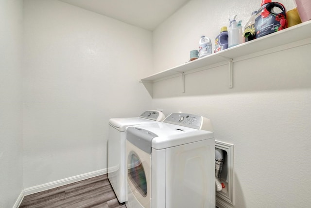 clothes washing area featuring washing machine and clothes dryer and wood-type flooring