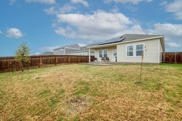 back of house with a yard, solar panels, and a patio