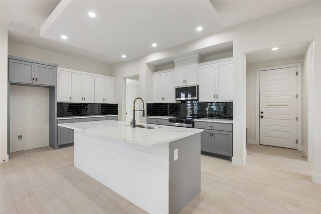 kitchen featuring sink, an island with sink, gray cabinets, and stainless steel appliances