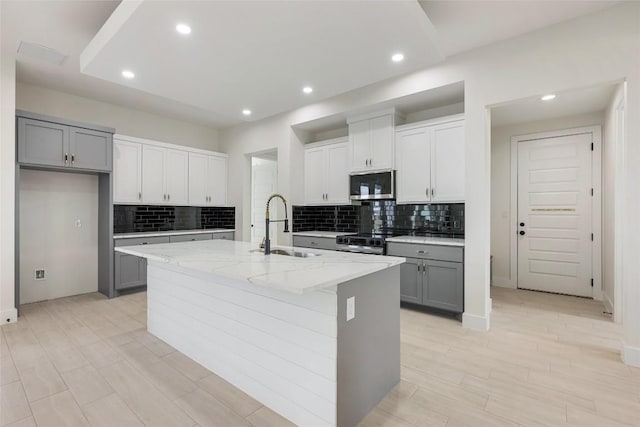 kitchen with a sink, tasteful backsplash, appliances with stainless steel finishes, and gray cabinets