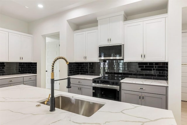 kitchen with stainless steel microwave, range with electric cooktop, gray cabinetry, and a sink