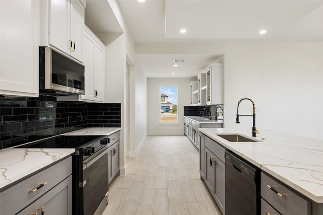 kitchen featuring electric range oven, black dishwasher, light stone countertops, white cabinets, and sink