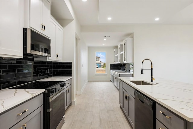 kitchen with electric stove, a sink, dishwasher, gray cabinets, and stainless steel microwave