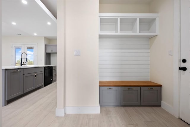 mudroom featuring recessed lighting, baseboards, a sink, and light wood-style floors
