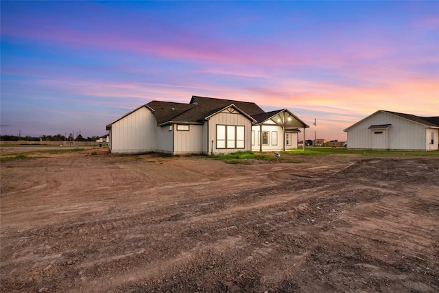 back of property at dusk featuring board and batten siding