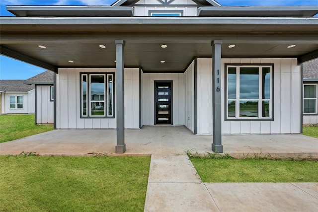 view of front of home with board and batten siding, a front lawn, and covered porch