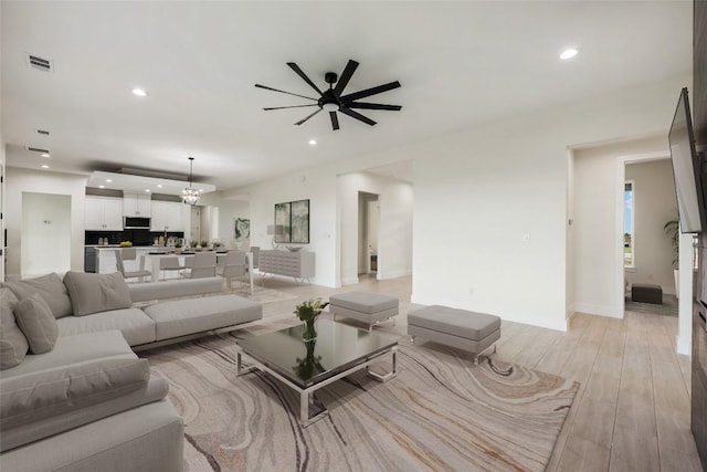 living area with visible vents, baseboards, recessed lighting, light wood-style floors, and ceiling fan