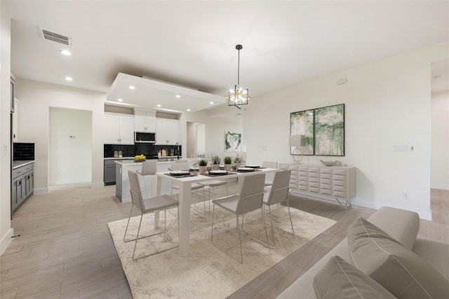 dining room featuring light wood finished floors, baseboards, visible vents, and recessed lighting
