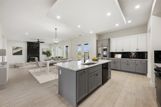 kitchen with ceiling fan, gray cabinets, pendant lighting, sink, and a kitchen island with sink