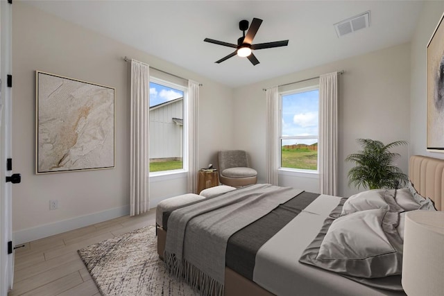 bedroom with baseboards, a ceiling fan, visible vents, and light wood-style floors