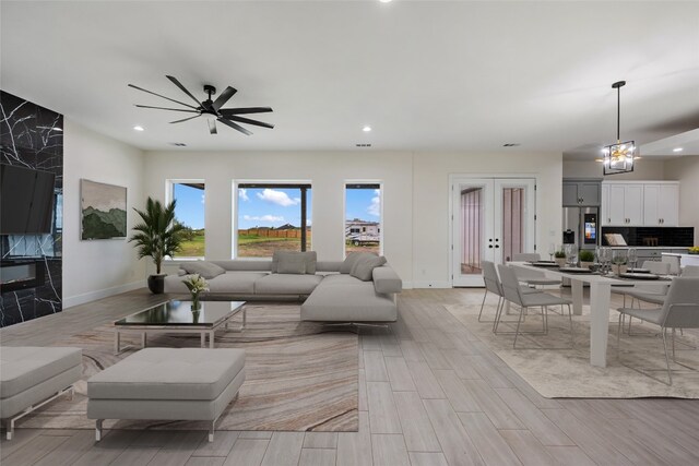 living room with ceiling fan with notable chandelier and french doors