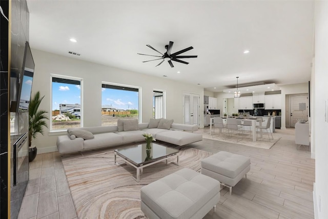living area with light wood-type flooring, baseboards, visible vents, recessed lighting, and ceiling fan