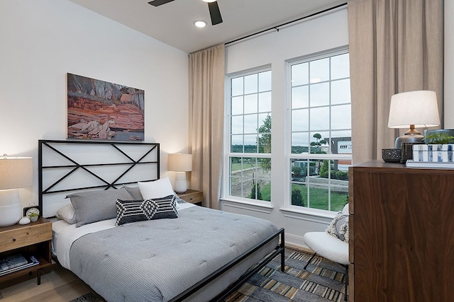 bedroom with multiple windows, hardwood / wood-style floors, and ceiling fan