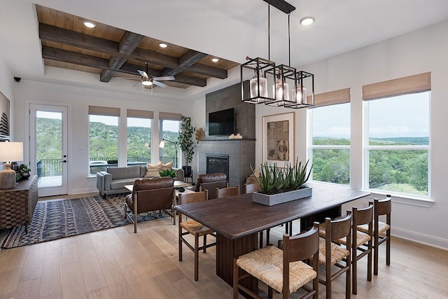 dining room featuring light hardwood / wood-style floors, coffered ceiling, a wealth of natural light, and a tile fireplace