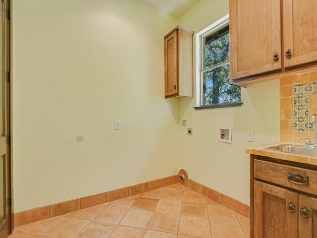 laundry area featuring hookup for a washing machine, light tile patterned floors, hookup for an electric dryer, sink, and cabinets