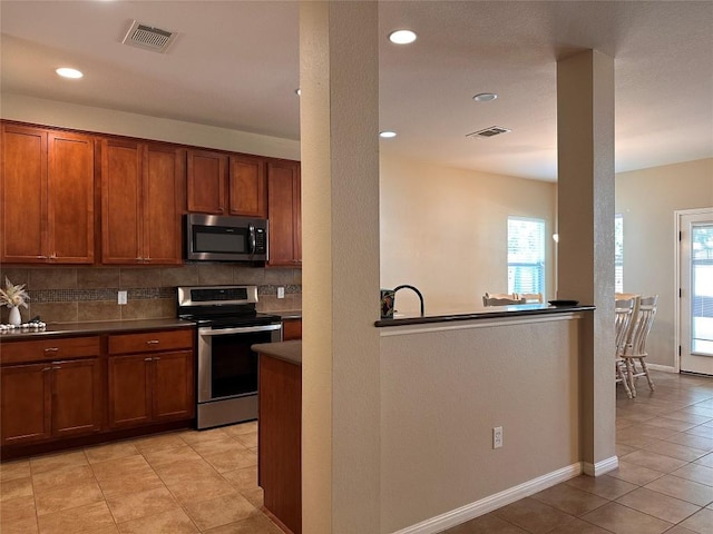 kitchen with appliances with stainless steel finishes, tasteful backsplash, light tile patterned floors, and a wealth of natural light