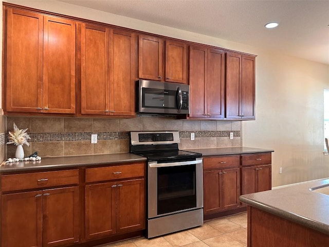 kitchen with backsplash, light tile patterned floors, and stainless steel appliances