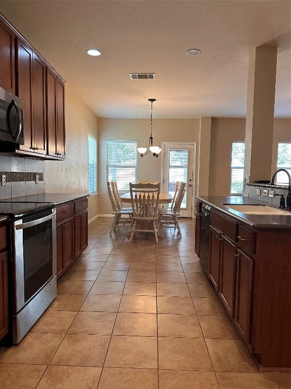 kitchen featuring plenty of natural light, hanging light fixtures, sink, and appliances with stainless steel finishes