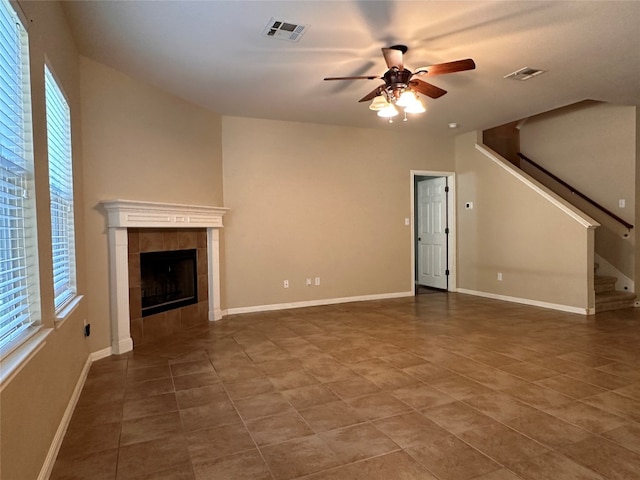 unfurnished living room with a tile fireplace, dark tile patterned flooring, plenty of natural light, and ceiling fan