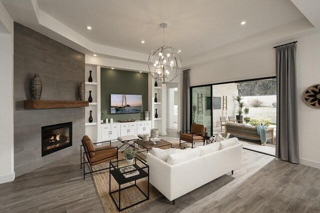 living room featuring hardwood / wood-style floors, a chandelier, a tile fireplace, and built in features