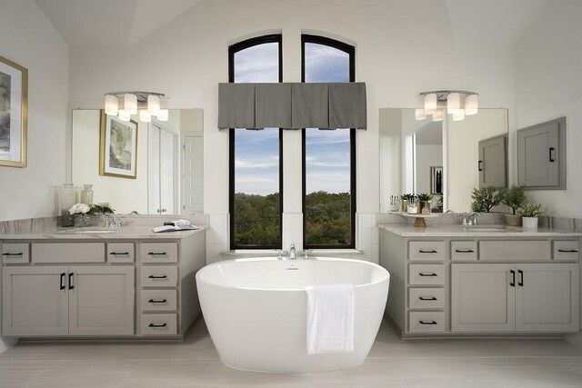 bathroom featuring vanity, a bathtub, tile patterned floors, and lofted ceiling