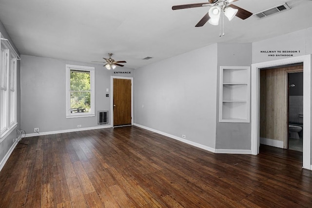 empty room featuring dark wood-type flooring, ceiling fan, and heating unit