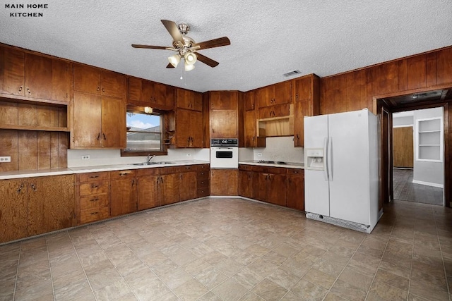 kitchen with white appliances, sink, ceiling fan, and a textured ceiling