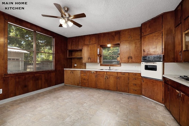 kitchen featuring a wealth of natural light, ceiling fan, white appliances, and a textured ceiling